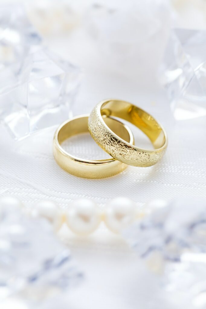 Two golden rings with pearl necklace and on white background